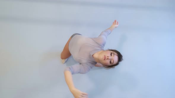 The girl dances a modern dance in a bright studio. Slow and smooth movement. View from above.