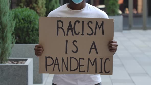 RACISM IS A PANDEMIC on a Cardboard Poster in the Hands of an African American Rights Activist