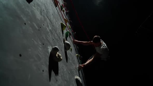 Guy Training on a Climbing Wall Practicing Rockclimbing and Moving Up Using Insurance Cinematic