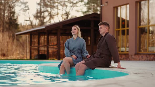 Honeymooners are Resting in Modern Spa Hotel with Outdoor Swimming Pool Young Man and Woman in Gowns