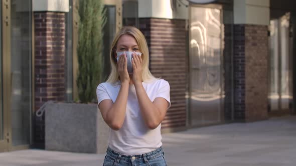 Portrait of Pretty Young Woman Looking Into the Camera and Putting on Medical Mask on Face for