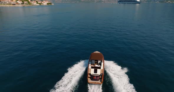 speeding boat in kotor bay with cruise ship on background and mountains