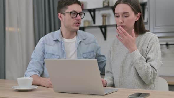 Young Couple Reacting To Loss on Laptop in Living Room 