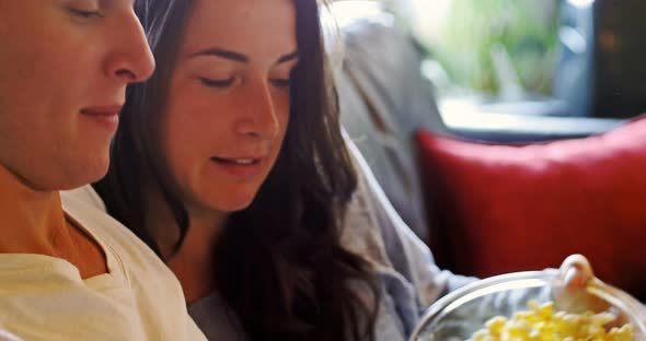 Couple eating popcorn while using digital tablet