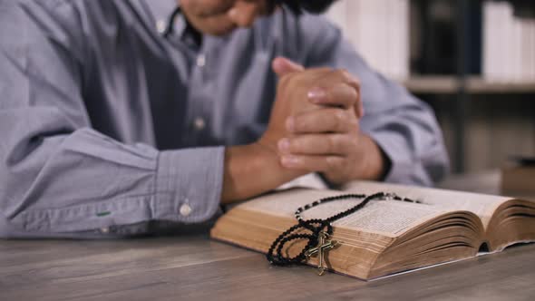 A young Christian man sitting in a church praying to God. alt