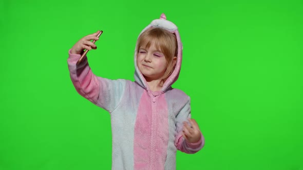 Child Girl in Unicorn Costume Pajamas Using Smartphone Kid Emotionally Makes Selfie on Mobile Phone