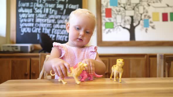 Blonde Toddler Girl Playing with Toy Animals at the Nursery