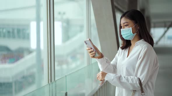 woman using smartphone and wearing medical mask for prevention from coronavirus (Covid-19) pandemic