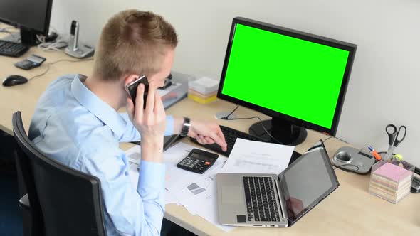 Young Handsome Man Sits and Works on Desktop Computer in the Office and Phone - Green Screen