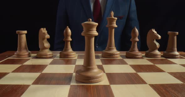 Close Up of Businessman Moving White Knight on Chessboard Isolated on Black Background