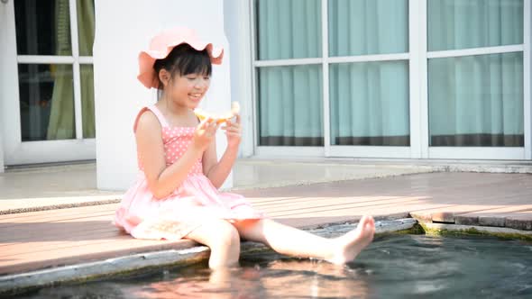 Little Asian Girl Eating Melon and Splashing Around In The Pool