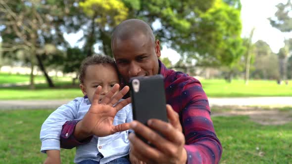 African American Father Waving and Making Selfie with Son