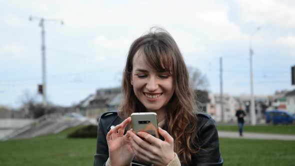 Portrait of Happy Young Caucasian Beautiful Female Portrait in City and Texting on Smartphone