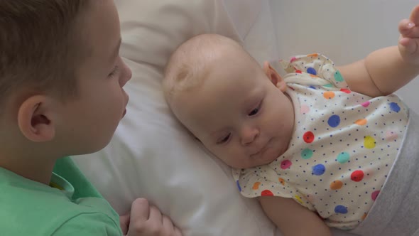 Boy Lying on a Bed with His Baby Sister and Stroking on Her Head