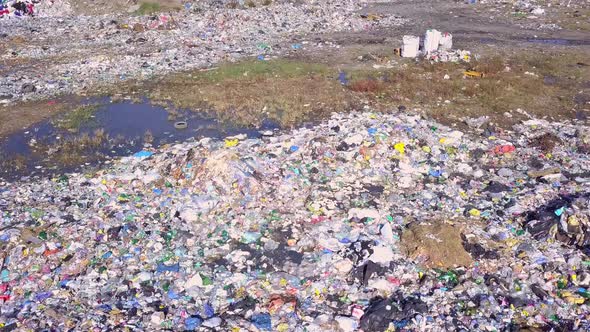 Drone view of city dump on background of sea, the city and the mountains.