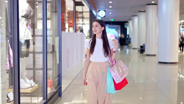 Brunette Shopaholic Walking Along Stores in Shopping Mall