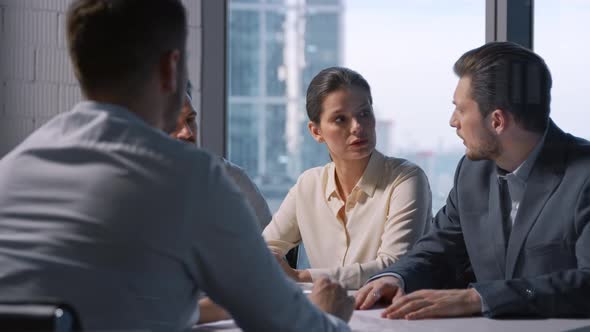 Successful mature businesswoman communicating with business partners while sitting at desk