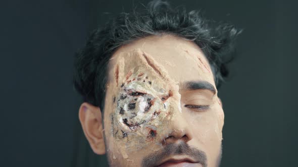 Make up artist coloring prosthetic insert on man's face and making Halloween mask