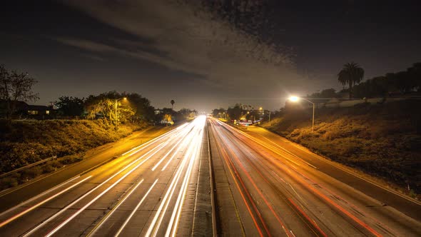 Time lapse of busy night traffic across freeway in Los Angeles. Blue sky with stars and scattered cl