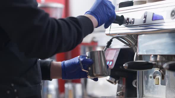 Unrecognizable Male Barista Cleaning Steam Wand After Steaming Milk in Coffee Machine Indoors