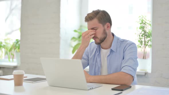 Young Creative Man with Laptop Having Headache