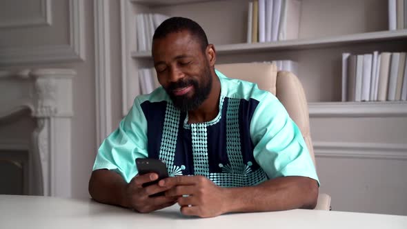 Cool Black Guy Is Switching on Favorite Music at Smartphone and Listening, Sitting in Room