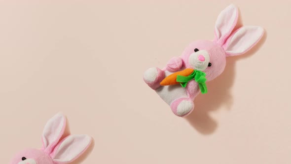 Pink Plush Little Easter Bunny with a Red Carrot on a Pastel Beige Background