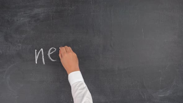 A man's hand writes the phrase NEW SKILLS on a chalkboard