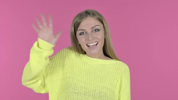 Attractive Young Girl Waving at Camera Pink Background