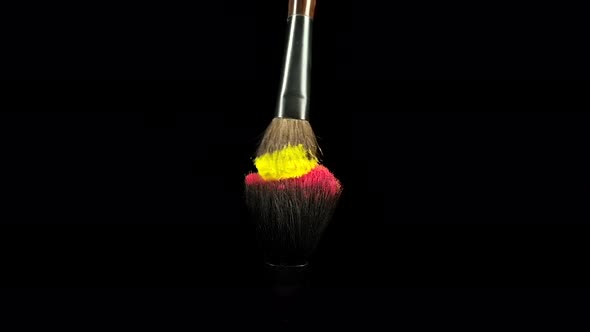 Makeup Brushes Touch Each Other on Black Dark Background and Small Particles of Color Cosmetics