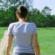 A Girl Walks Along a Country Road in a Green Meadow Surrounded By Forest - VideoHive Item for Sale