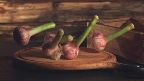 Super Slow Motion Garlic Falls on a Cutting Board on a Wooden Background