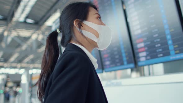 Asian business girl wear face mask with suitcase stand in front of board look at information.