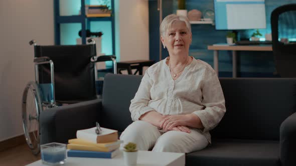 Portrait of Retired Woman with Disability Sitting on Sofa