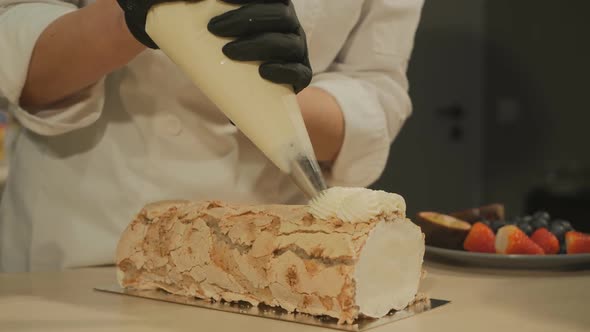 Woman Pastry Chef Squeezes Butter Cream on Meringue Roll