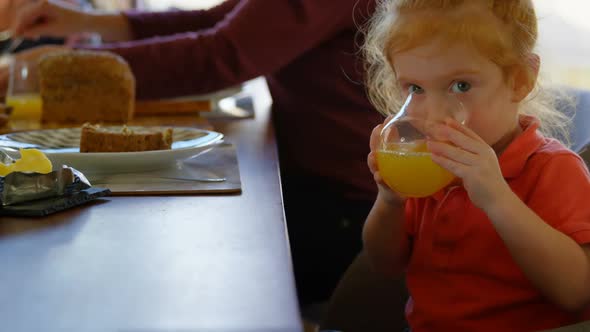 Cute little boy drinking orange juice at dining table 4k