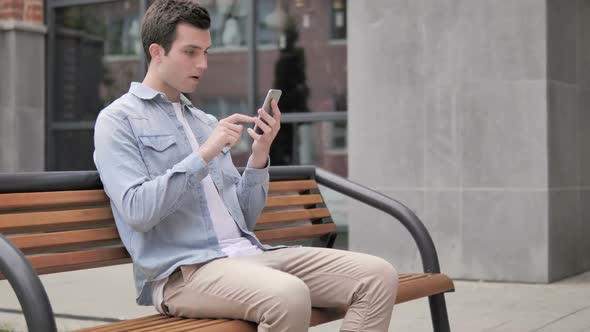 Outdoor Young Man Upset By Loss While Using Smartphone