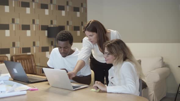 Group of Diverse Coworkers Sitting and Standing at Table