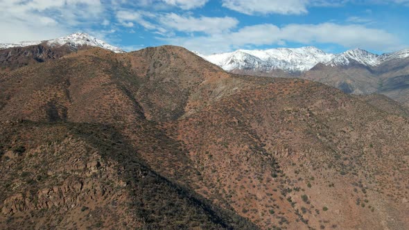 Aerial view dolly in from Morro Las Papas, San Carlos de Apoquindo Park, snowcapped mountain in the