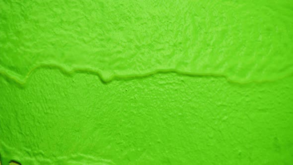 Green Neon Paint Dripping on Yellow Wall Closeup