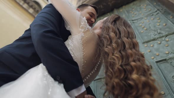 Newlyweds Caucasian Groom with Bride Walking Embracing Hugs on the City Street Wedding Couple