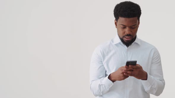 Concentrated African man texting by phone