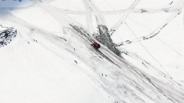 Aerial View Red Modern Snowcat Ratrack Descends From the Slopes of the Mountain Along a Rolled Road