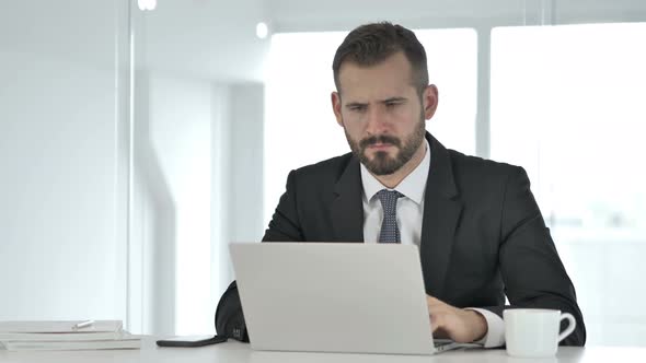 Pensive Businessman Thinking and Working on Laptop