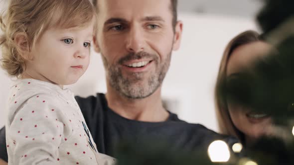 Toddler and her parents next to a Christmas tree. Shot with RED helium camera in 8K.