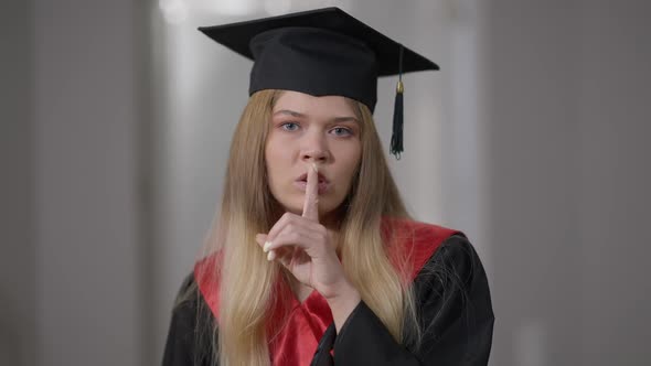 Portrait of Beautiful Caucasian Young Graduate Woman Gesturing Finger on Lips Hush Gesture Looking