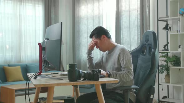 Asian Cameraman Being Tired While Using Desktop Computer For Working At Home