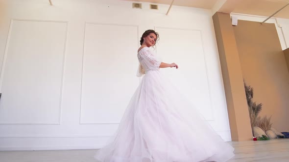 A Beautiful Bride in a White Dress Poses for a Photographer Standing Whirls