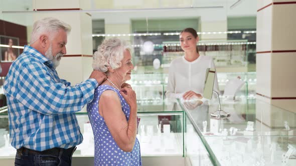 Charming Old Lady Trying on Pearl Necklace at Jewelry Store