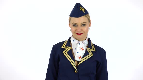 A Young Beautiful Stewardess Applauds and Smiles at the Camera - White Screen Studio